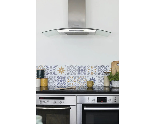 Küchenszene mit Dunstabzugshaube, Fliesenaufklebern, Geschirr und Backöfen