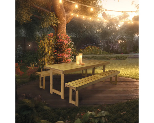 Gartenszene mit Holztisch und Bänken unter einer Lichterkette
