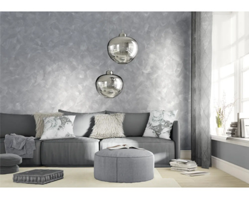 Wohnzimmer mit Sofa, Kissen, Hocker und dekorativer Wandgestaltung.