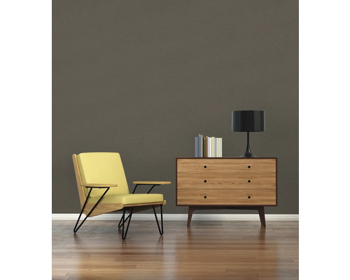 Wohnzimmer mit Sessel, Kommode, Lampe und Büchern