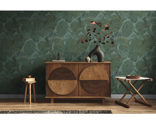 Wohnzimmer mit grüner Blättertapete, Holzkommode und Hockern