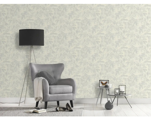 Ein Zimmer mit einer gemusterten Tapete, einem Sessel und einer Stehlampe.