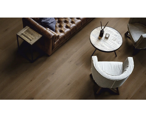 Wohnzimmer mit braunem Ledersofa, Holztischen und Holzboden.