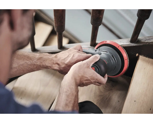 Mann schleift Holztreppe mit Exzenterschleifer.