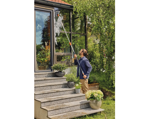 Mann reinigt Fenster mit Teleskop-Fensterwischer an einem Wintergarten