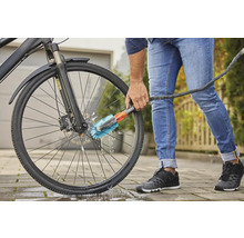 Person reinigt ein Fahrrad mit einer Bürste und einem Wasserschlauch.