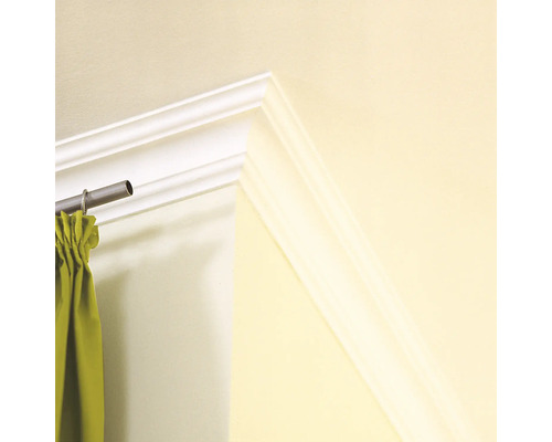 Detailaufnahme einer weißen Zierleiste an einer Wand mit Gardinenstange und Gardine.