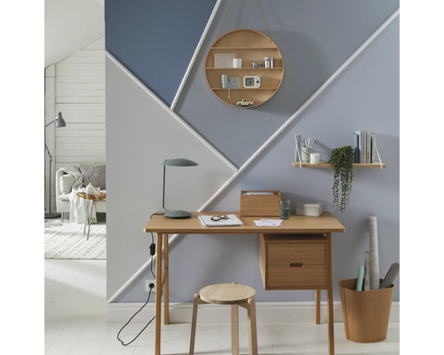 Bürozimmer mit Schreibtisch, Stuhl, Wandregalen und geometrischen Farbmustern an der Wand.