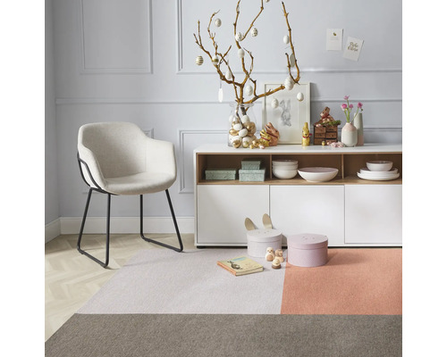 Dekoratives Wohnzimmer mit Sessel, Kommode und Teppich in harmonischen Farben