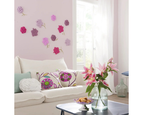 Wohnzimmer mit weißem Sofa, Zierkissen und Wanddekoration mit Blumenmotiven