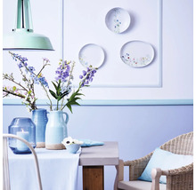 Helles Esszimmer mit Tisch, Stuhl, Vasen und dekorativen Tellern an der Wand