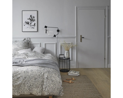 Schlafzimmer mit Bett, Nachttisch, Lampe und Teppich