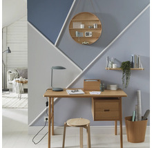 Arbeitszimmer mit Schreibtisch, Stuhl, Regalen und geometrischer Wandgestaltung