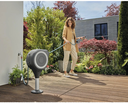 Frau benutzt eine Gardena Schlauchbox auf einer Terrasse mit Holzboden