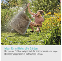 Mann bewässert mit einem Gartenschlauch einen grossen Pflanzentopf im Garten
