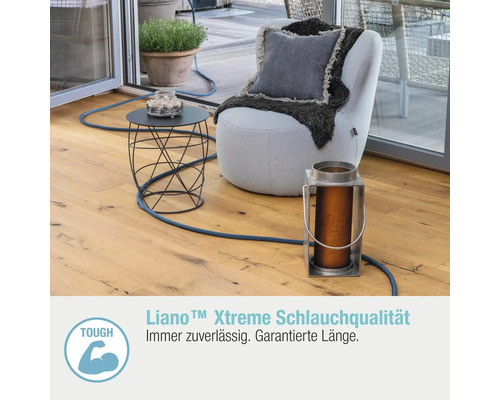 Szene mit Sitzgelegenheit, Tisch und Gartenschlauch auf einer Terrasse