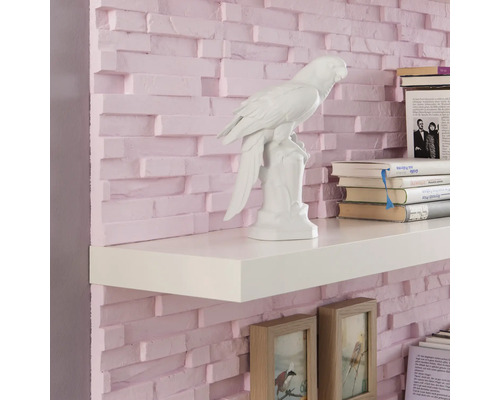 Wandregal mit Dekorationsgegenständen und Büchern vor einer Ziegelwand