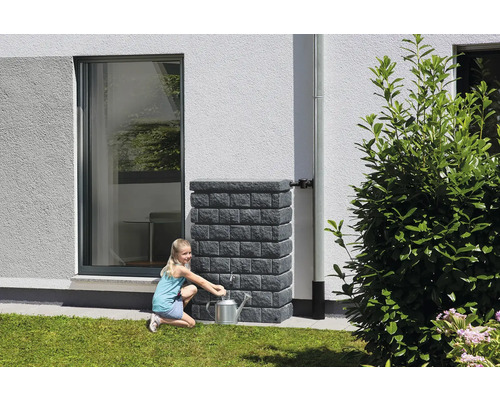 Mädchen befüllt Gießkanne an Regenwassertank