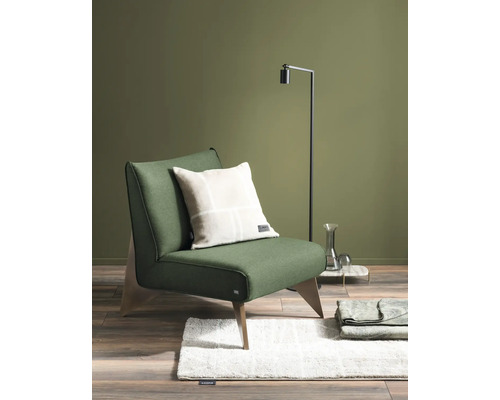 Szene mit Sessel, Kissen, Stehlampe, Teppich und Überwurf auf Holzboden