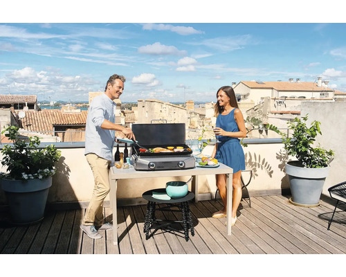 Szene auf einer Dachterrasse mit einem Paar beim Grillen auf einem Tischgrill