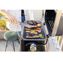 Person grillt Gemüse und Fleisch auf einem Grill.
