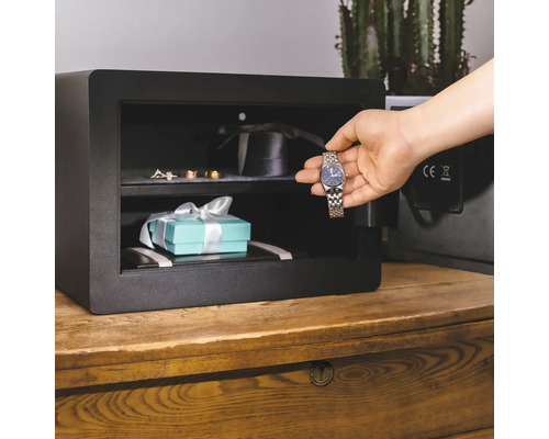 Geöffneter Möbeltresor mit Schmuck und Uhr auf einem Holzschrank