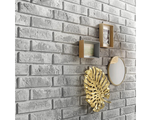 Wandgestaltung mit Steinoptik und dekorativen Elementen wie Bilderrahmen, Spiegel und Blattornament