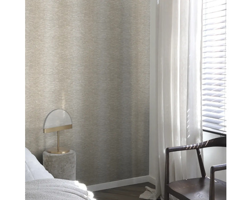 Ein Schlafzimmer mit einer strukturierten Tapete an der Wand, einem Nachttisch mit Lampe und einem Stuhl am Fenster.