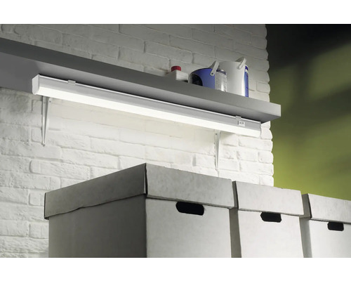 Regal mit LED Unterbauleuchte und Aufbewahrungsboxen vor einer Ziegelwand.