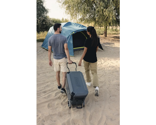 Personen ziehen Kühlbox mit Rädern zum Campingzelt der Marke Coleman.