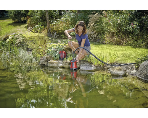 Frau benutzt Teichpumpe im Gartenteich