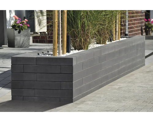 Lange, gemauerte Pflanzbox aus Betonsteinen mit Pflanzen