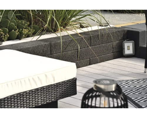 Terrassenszene mit Mauer aus Betonsteinen, LED-Strahler, Lounge Möbeln und dekorativer Laterne
