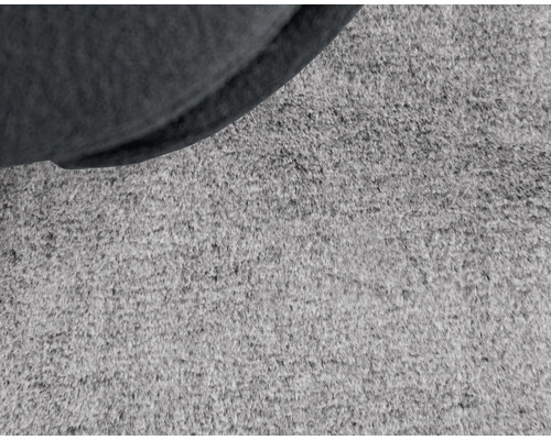 Detailaufnahme eines Teppichs mit einem Teil eines Sitzmöbels.