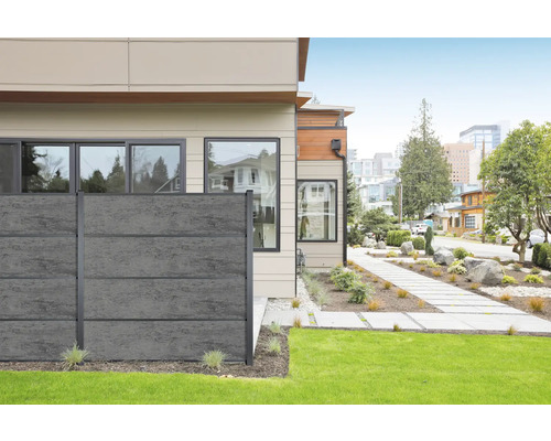 Modernes Haus mit grauer Betonzaun-Einfriedung zum Garten