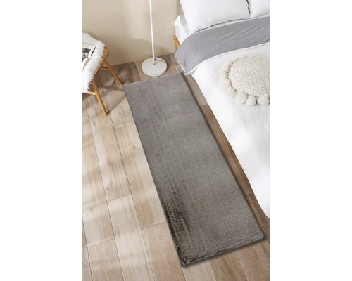 Grauer Teppich neben einem Bett auf einem Holzboden