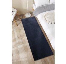 Schlafzimmer mit Bett, Leselampe, Stuhl und langem Teppich
