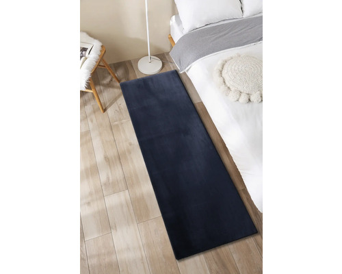 Schlafzimmer mit Bett, Leselampe, Stuhl und langem Teppich