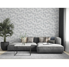 Wohnzimmer mit grauer Couch, Zimmerpflanze und Tapete mit Blattmuster