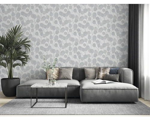 Wohnzimmer mit grauer Couch, Zimmerpflanze und Tapete mit Blattmuster