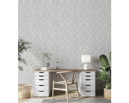 Helles Arbeitszimmer mit floral gemusterter Tapete, Schreibtisch, Stuhl und Zimmerpflanzen