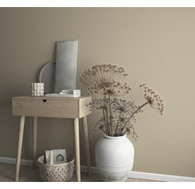 Dekoratives Arrangement mit Beistelltisch, Vase mit Trockenblumen und Dekorationselementen vor einer einfarbigen Wand.