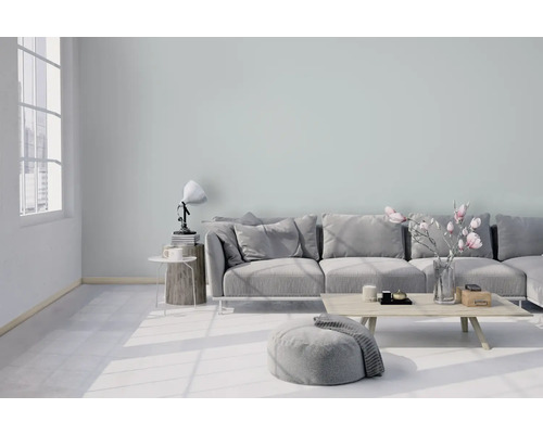 Helles Wohnzimmer mit Couch, Hocker, Tisch und Dekoration