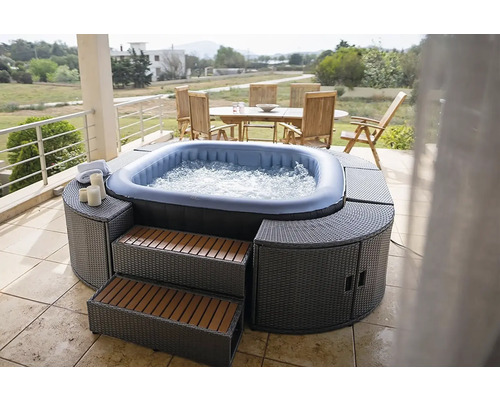 Aufblasbarer Whirlpool mit Umrandung und Treppe auf einer Terrasse mit Gartengarnitur