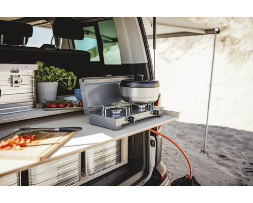 Campingküche im Kofferraum eines Vans mit Gaskocher, Kochgeschirr und Zutaten.