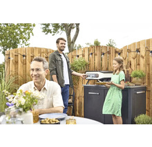 Familie bereitet Essen mit einem Pizzaofen im Garten zu.