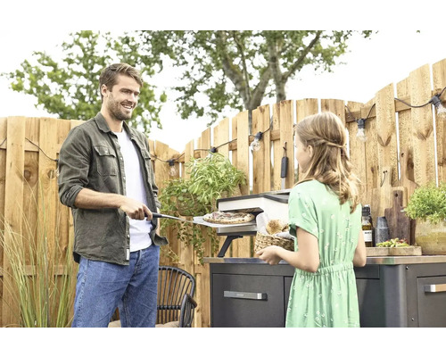 Mann und Mädchen bereiten Pizza im Außenbereich zu