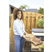Frau mit zwei Pizzen auf Holzbrettern im Garten am Pizzaofen