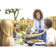 Eine Frau serviert Pizza bei einem Gartenfest.