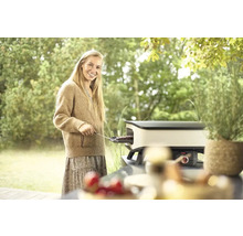 Frau grillt auf einem Tischgrill im Garten.